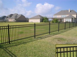 A three rail flat top ornamental iron fence stretch across an expansive yard