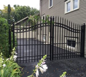 A black ornamental iron overscallop estate gate near the side of a house