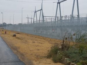 A high security fence protecting several large industrial features